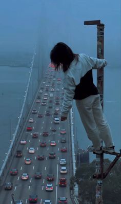 a person on a skateboard is standing on the edge of a high - rise bridge