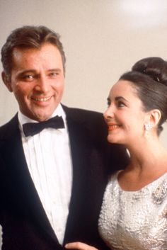 a man in a tuxedo standing next to a woman