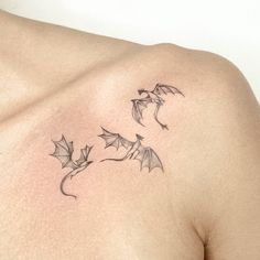 a tattoo on the back of a man's shoulder with bats flying around it