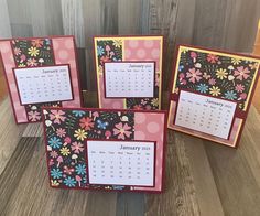 three calendars with flowers on them are placed next to each other in front of a wooden wall