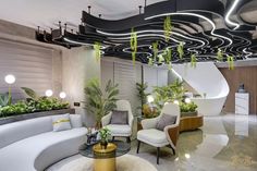 a living room filled with white furniture and lots of plants on top of it's walls