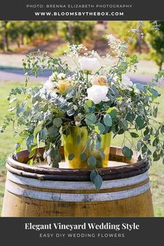 a vase with flowers sitting on top of a barrel