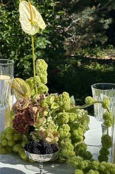 the table is set with grapes, flowers and other items for an outdoor dining area