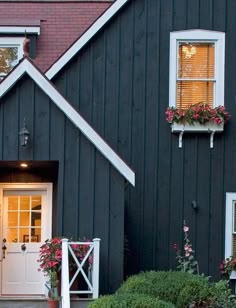 an instagram photo of a black house with white shutters and flowers in the window