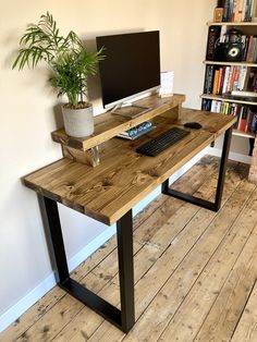 a wooden desk with a computer monitor and keyboard on it in front of a bookshelf