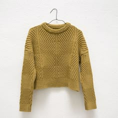 a yellow sweater hanging on a white wall