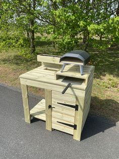 a wooden work bench with tools on it in the middle of a road next to some trees