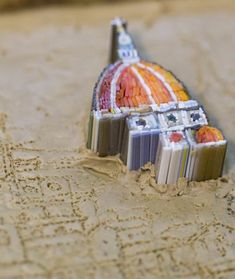 a close up of a toothbrush in the sand with writing on it and a building made out of books