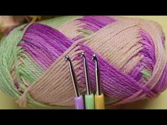 three skeins of yarn with crochet hooks in front of one ball of yarn