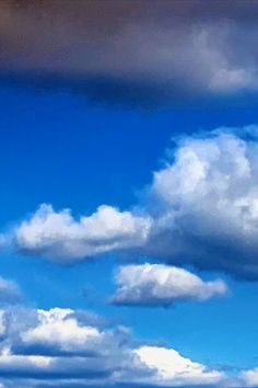 the airplane is flying high in the blue sky with white clouds above it and on the ground below