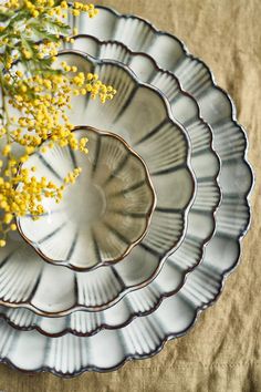 a vase with yellow flowers in it sitting on a cloth covered tablecloth next to a plate