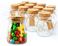 small glass jars filled with different colored candies and brown paper tags tied to them