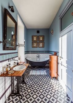 a bathroom with blue walls and black and white tiles on the floor, along with a claw foot tub