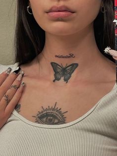 a woman with tattoos on her chest and eye in front of her neck is looking at the camera