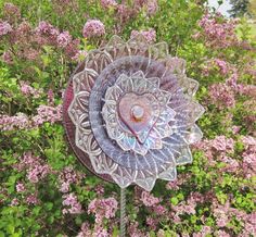 a glass sculpture in the middle of some flowers