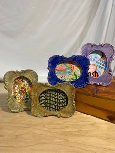 three decorative frames sitting on top of a wooden table