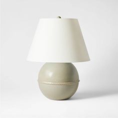 a white table lamp sitting on top of a wooden table next to a white wall