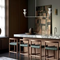 a kitchen with marble counter tops and stools in front of a large painting on the wall