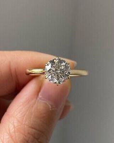 a woman's hand holding an engagement ring with a diamond in the middle,