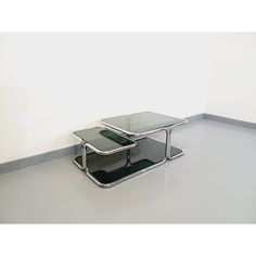 two glass tables sitting next to each other on top of a white floor in an empty room