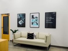 a white couch sitting next to a wooden table in a room with pictures on the wall