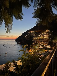 a view of the ocean at night with lights on and boats in the water below