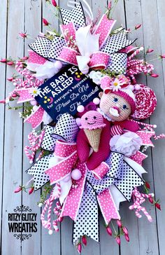 a pink and white wreath with two stuffed animals