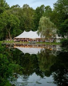 a tent is set up by the water for an outdoor party