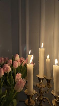 a group of candles sitting on top of a table with flowers in front of it