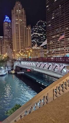 the city skyline is lit up at night with lights reflecting in the water and boats on the river