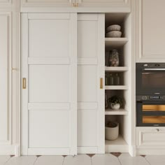 an open door to a kitchen with white cupboards and appliances on the wall next to it