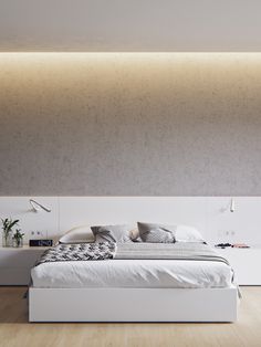 a white bed sitting in the middle of a bedroom next to a wall mounted lamp