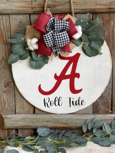 a wooden sign with the letter a on it and greenery around it that says roll tide