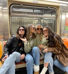 three women sitting on a subway bench next to each other