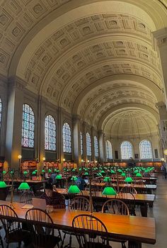 the interior of a large library with tables and green umbrellas on top of them