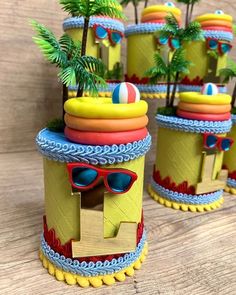 three small toy houses with palm trees and sunglasses on the top one is made out of cardboard