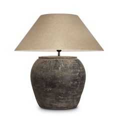 a lamp that is sitting on top of a white surface with a beige shade over it