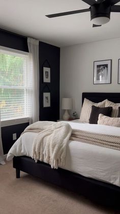 a bedroom with black walls and white bedding, two pictures on the wall above the bed