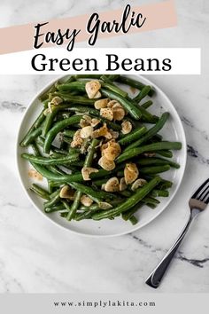 green beans with walnuts on a white plate next to a silver fork and spoon