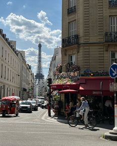 the eiffel tower is seen in the distance as people ride bikes down the street