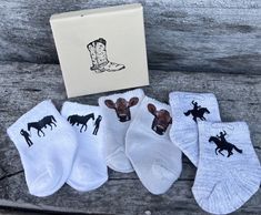 five pairs of socks with cowboy boots and horses on them, sitting next to a box