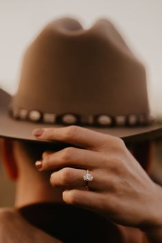 a woman wearing a brown hat and diamond ring