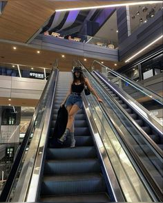 a woman is riding down an escalator with her luggage on her handbag