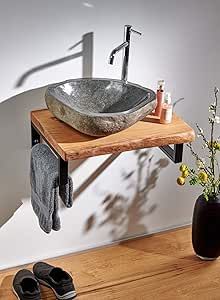 a bathroom sink sitting on top of a wooden counter next to a vase with flowers