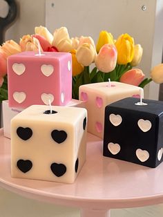 four dice candles with hearts on them sitting on a table next to tulips