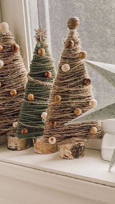 three small christmas trees made out of twine and seashells are sitting on a window sill