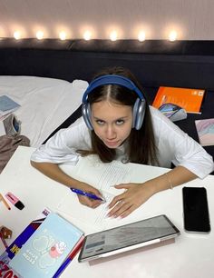 a young woman wearing headphones and writing on a notebook