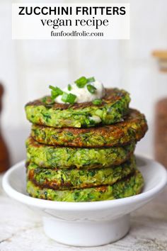 zucchini fritters on a white plate topped with sour cream and fresh herbs