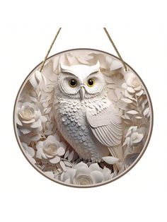 an owl sitting on top of a white flower filled circle with two strings hanging from it's sides