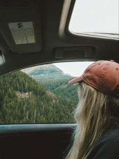 a person sitting in the back seat of a car looking out at mountains and trees